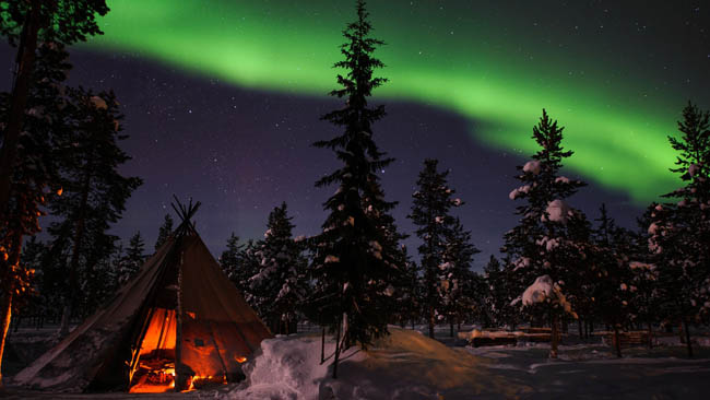 Northern Lights above tents at the reindeer lodge in Jukkasjärv
