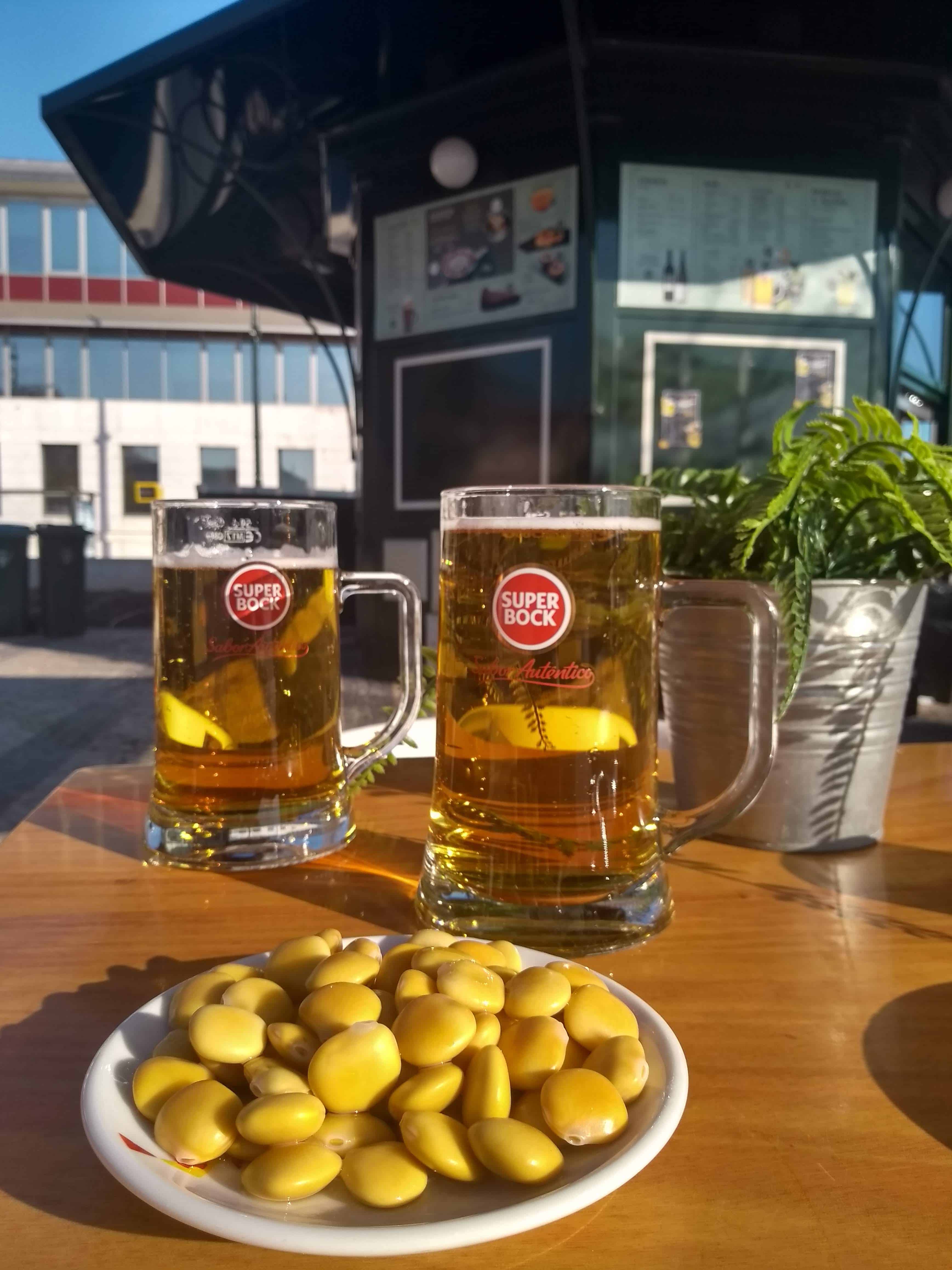 Porção de tremoços acompanhada de dois copos de cerveja da marca Super Bock