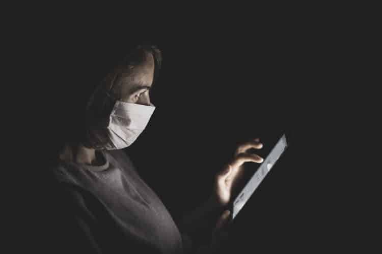 Mulher de máscara mexe no celular